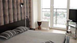 A bedroom with a large bed, a television, a glass cabinet, and a view of the city through the window. - Most City Premium apartments (Dnipro)