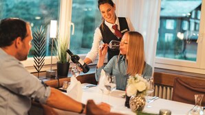 A restaurant setting with a waiter serving wine to guests. - Hotel Alpenhof (Unterbaech)