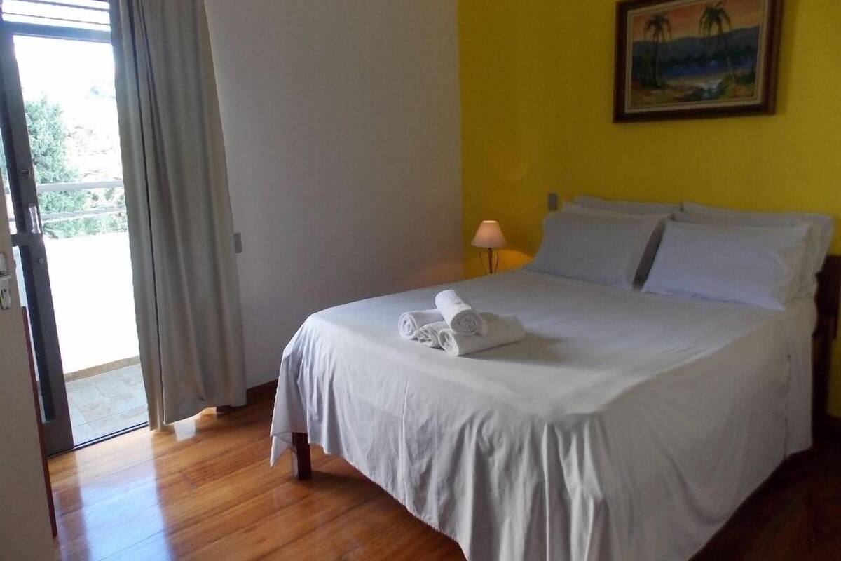 Una habitación de hotel con una cama, un cuadro en la pared y vistas a través de una puerta.