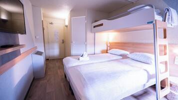 A hotel room with a bunk bed, a flat-screen TV, a desk, and a wooden floor.