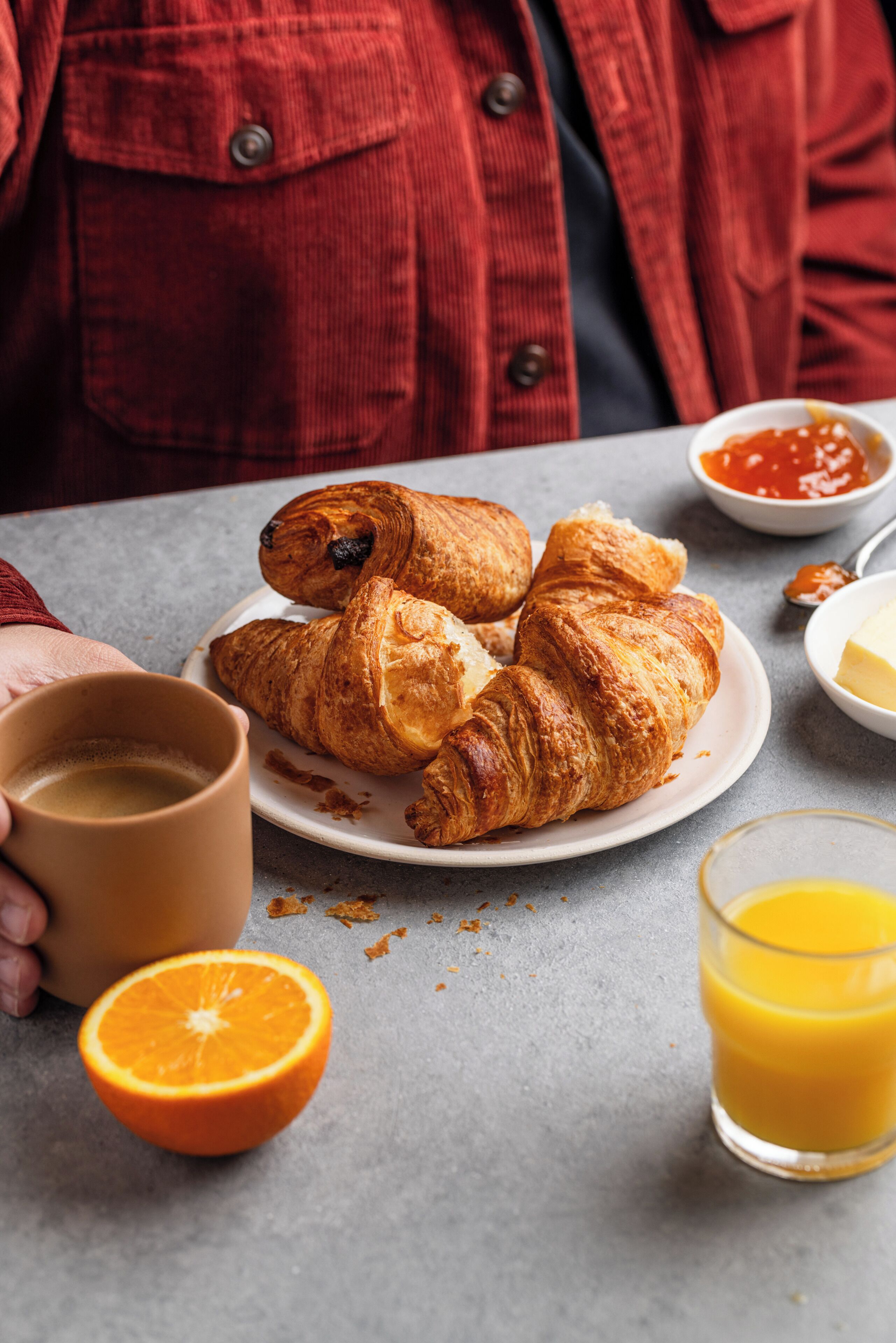 A plate with croissants, a glass of orange juice, and a cup of coffee on a table.