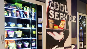 A vending machine with various snacks and drinks, a 'Cool Service' advertisement, and a digital display. - Hotel Ibis Budget Metz Sud Augny (Augny)