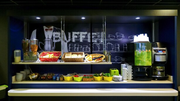 A buffet setup with various food items, a coffee machine, and a chalkboard menu. - ibis budget Marmande (Marmande)