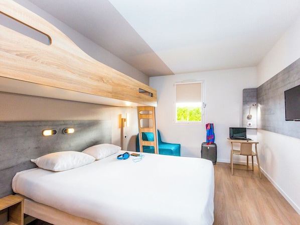 Una habitación de hotel moderna con literas, un escritorio, una silla y un ventanal.