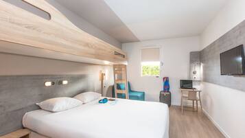 Una habitació d'hotel moderna amb una llitera, un escriptori amb un ordinador, una cadira i un televisor fixat a la paret.