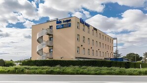 A building with a spiral staircase, a sign reading "This budget," and a flat roof. - ibis budget Marmande (Marmande)