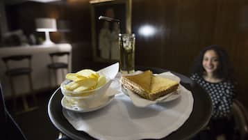 Una bandeja con un sándwich y papas fritas sobre una mesa en una habitación con poca luz, con un comedor al fondo.