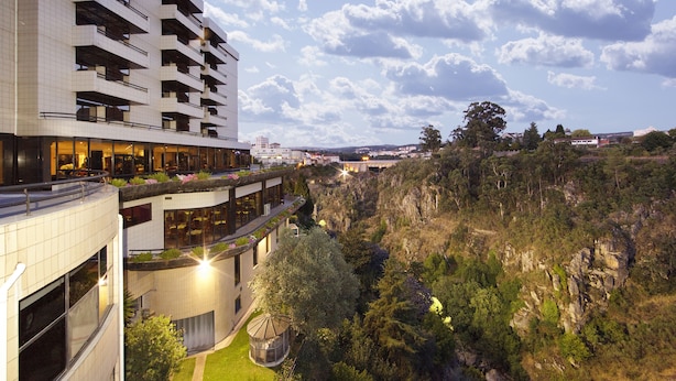 Un hotel moderno con varios pisos, terrazas al aire libre y un paisaje exuberante circundante.