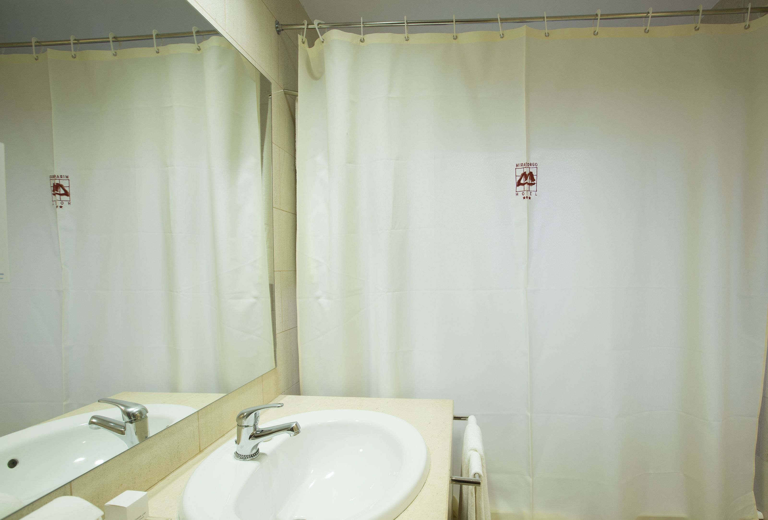 A bathroom with two sinks, a mirror, and a shower curtain.