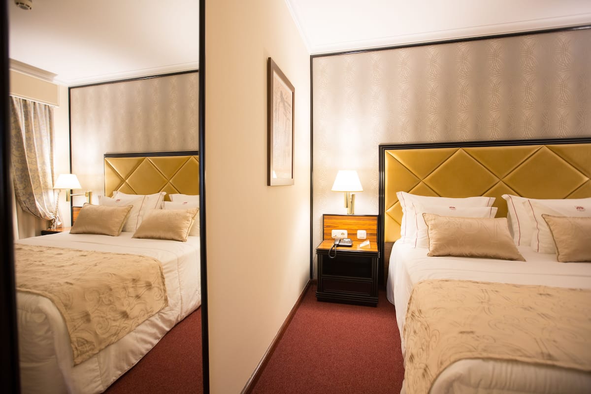 Ein Hotelzimmer mit zwei Betten, einem Nachttisch mit Lampe und einem gerahmten Bild an der Wand.