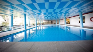 Una piscina interior con techo a cuadros y agua azul cristalina.
