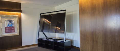Habitación de hotel con un espejo grande, televisor de pantalla plana y un mueble empotrado.