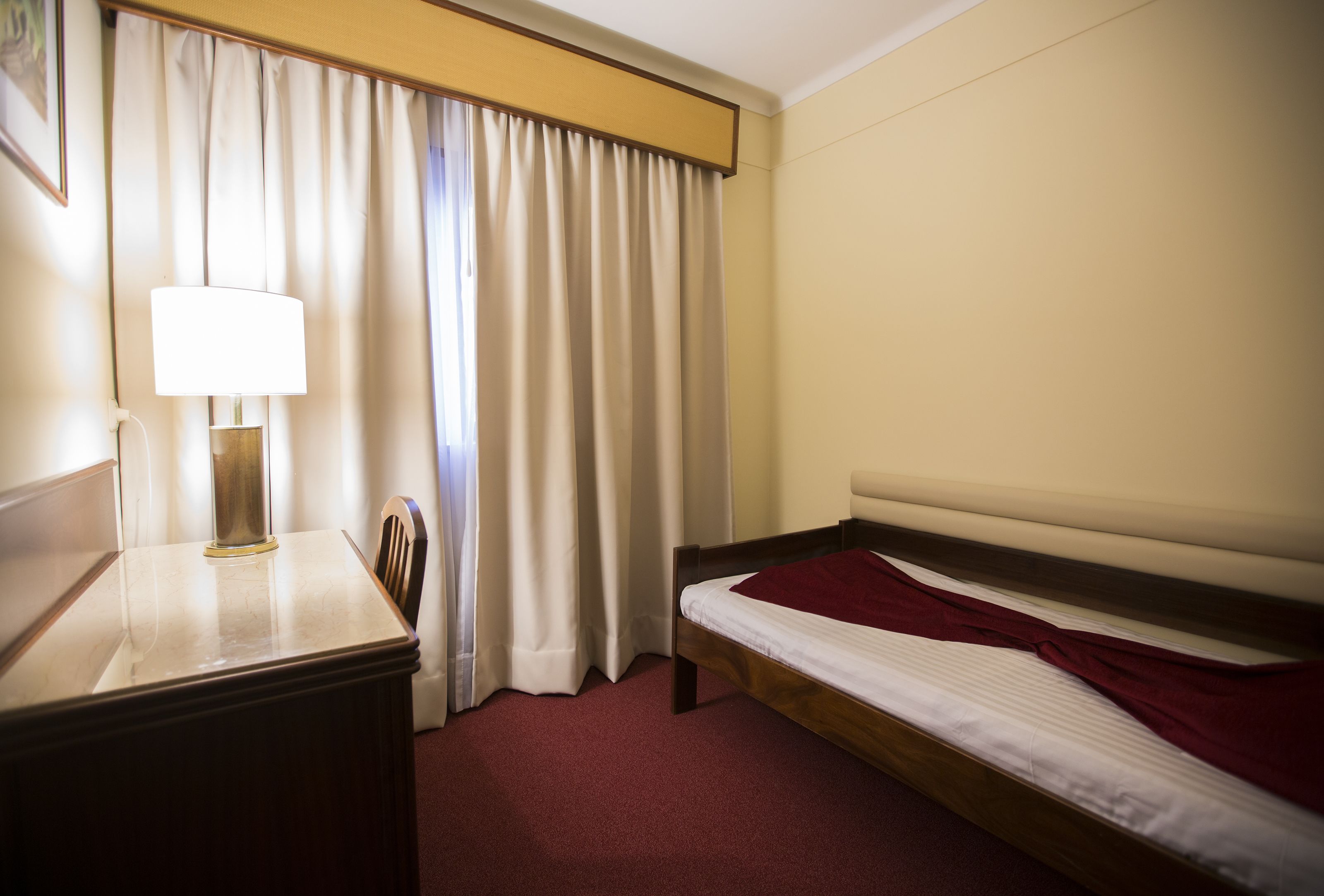 Una habitación de hotel con una cama, un escritorio con lámpara y una silla.