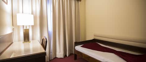 Una habitación de hotel con una cama, un escritorio con lámpara y una silla.