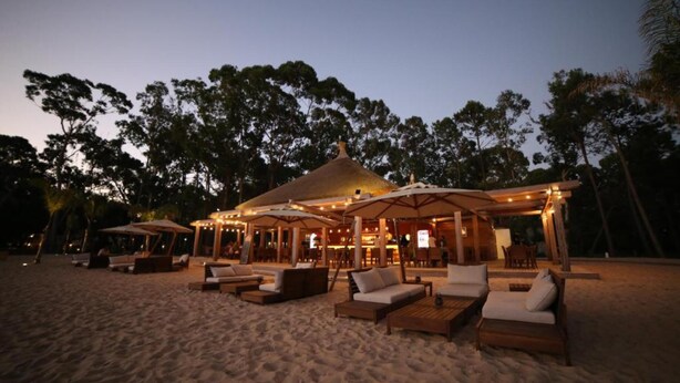 A beachside resort with outdoor seating areas, umbrellas, and a bar/lounge area.