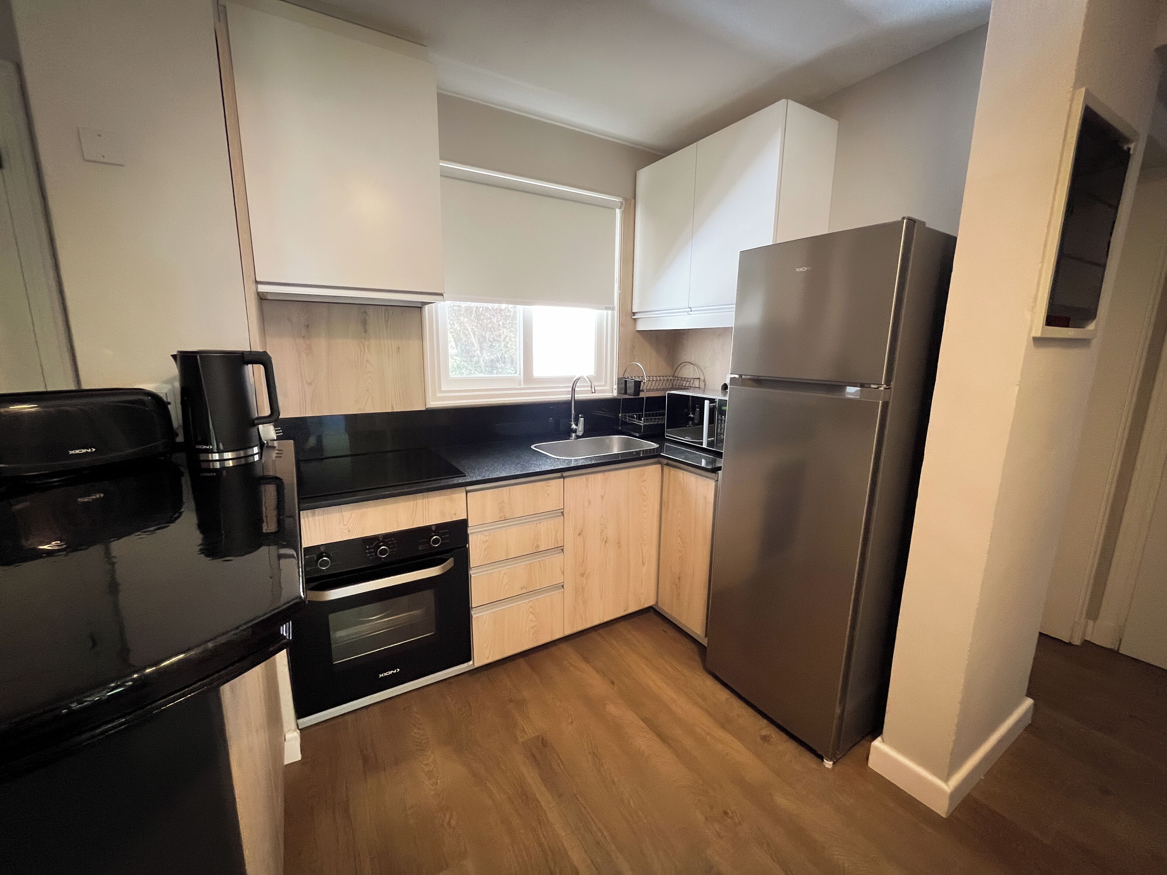 A modern kitchen with black appliances, wooden cabinets, and a stainless steel refrigerator.