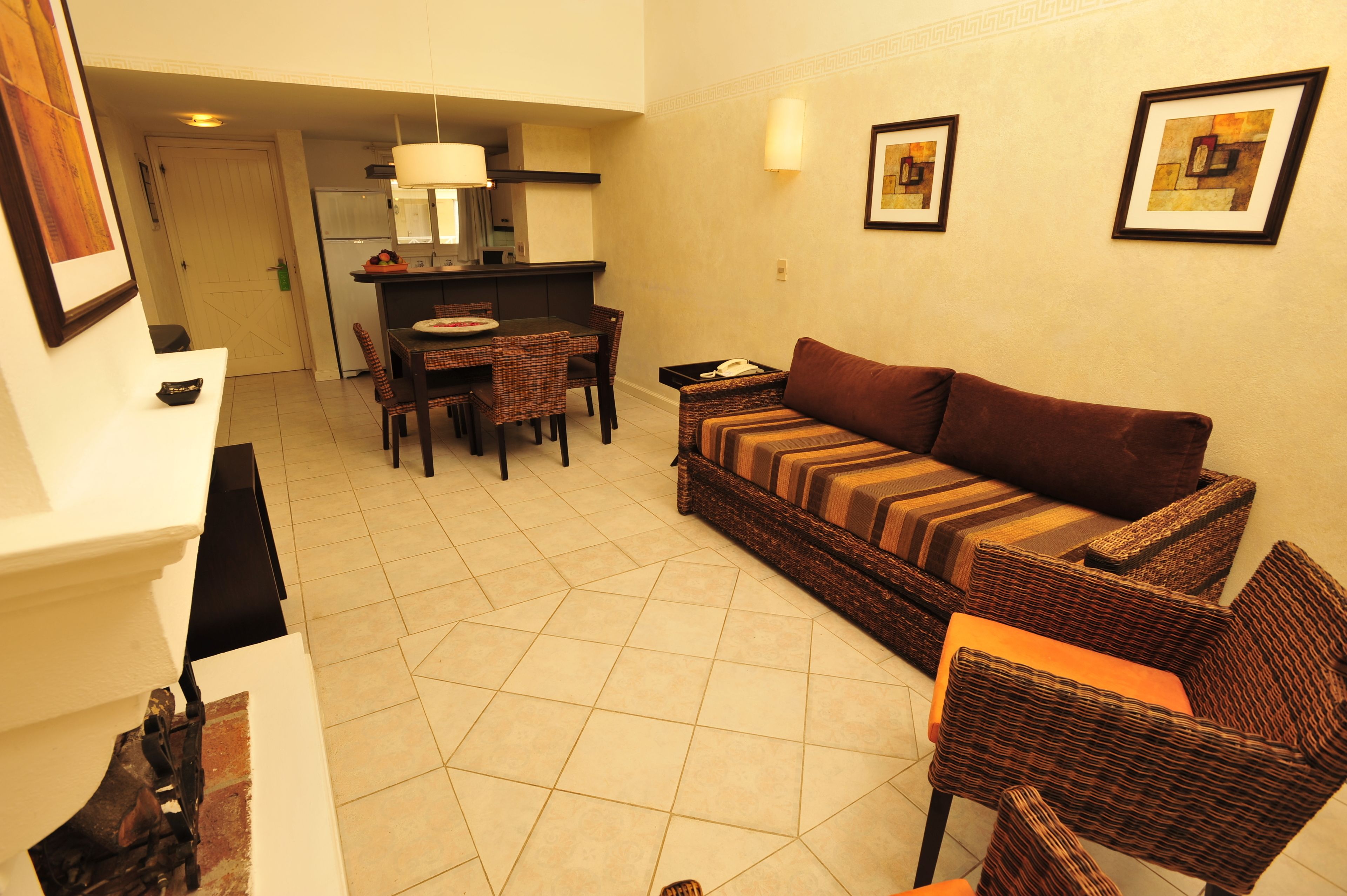 A living room with a sofa, chairs, a dining table, and a kitchen area in the background.