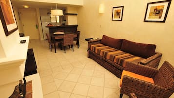 A living room with a sofa, chairs, a dining table, and a kitchen area in the background.