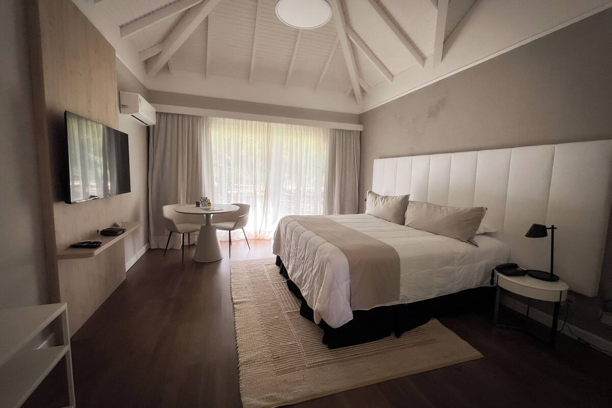 A modern hotel room with a large bed, a desk, and a TV.