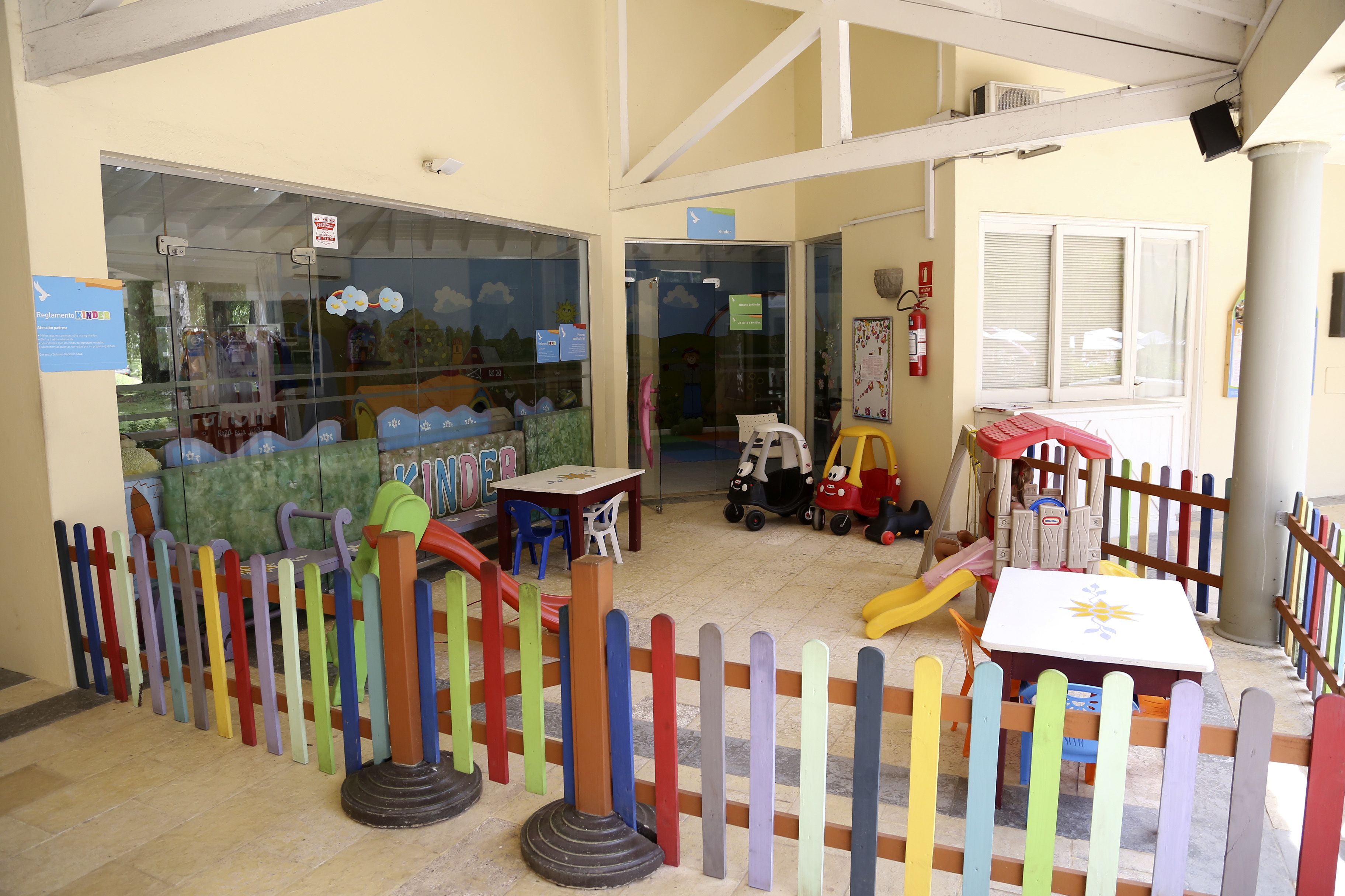 Un área de juegos infantiles con estructuras de juego coloridas, un tobogán y una mesa con sillas.
