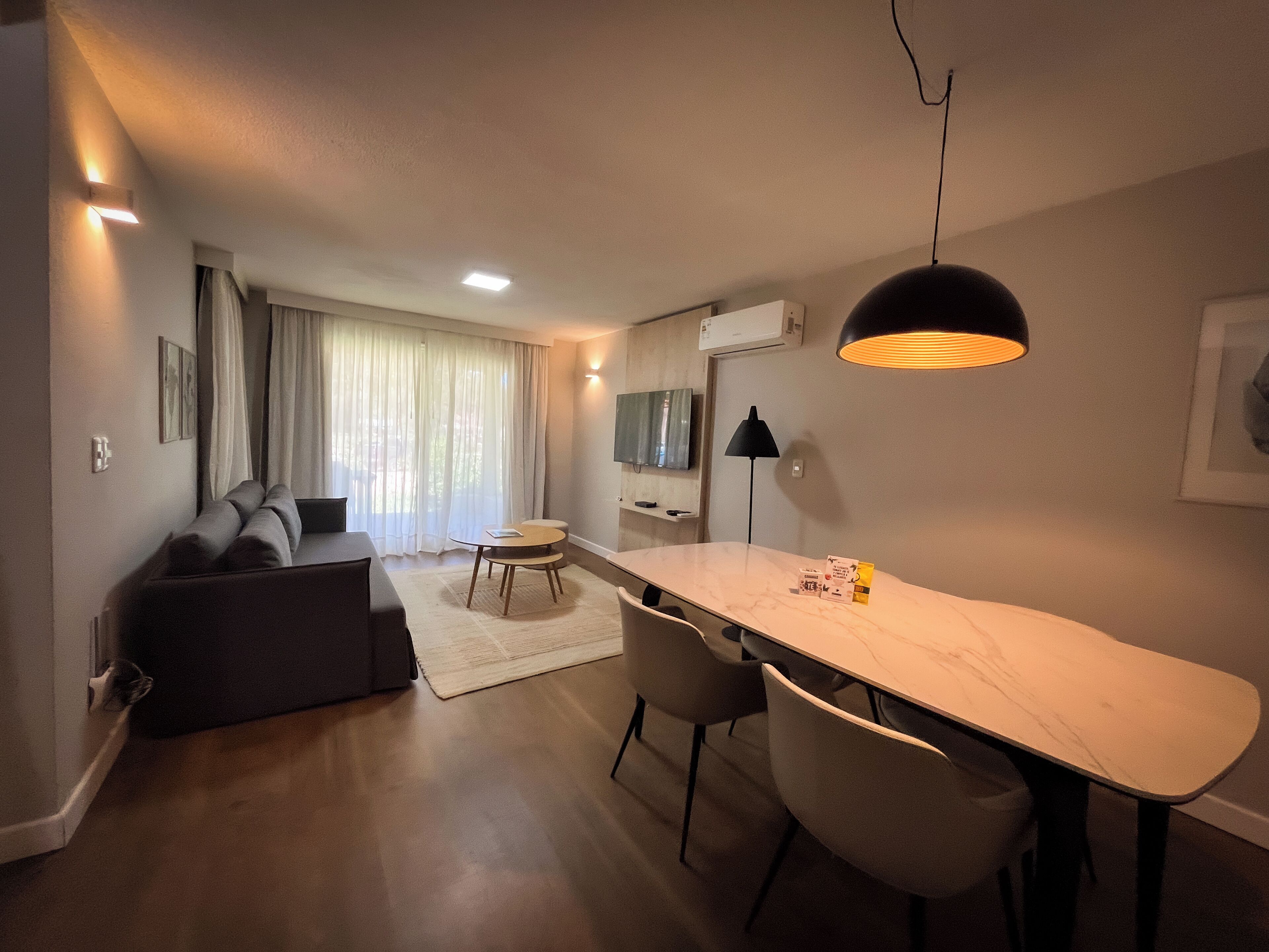 Un soggiorno moderno con un divano, un tavolo da pranzo con sedie, una TV e una lampada a soffitto.