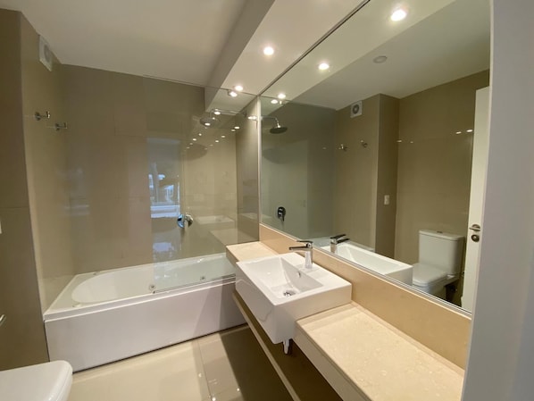 A modern bathroom with a glass-enclosed shower, a freestanding bathtub, and two sinks.