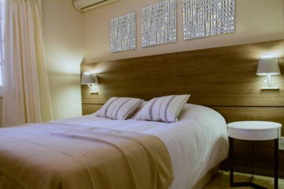 A hotel room with a large bed, two bedside lamps, a round side table, and decorative wall panels.