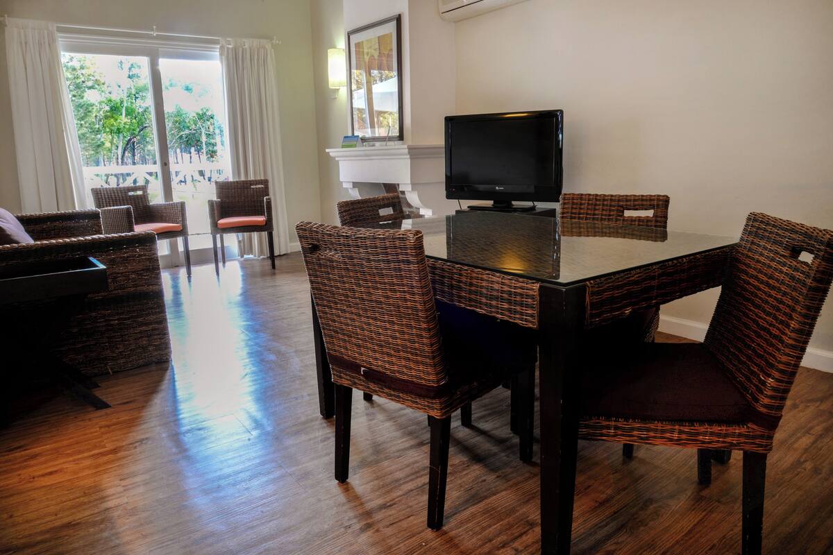 A dining area with wicker chairs, a table, and a TV.