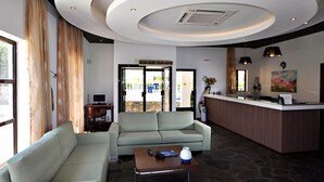 A modern hotel lobby with a reception desk, a sofa, and a coffee table. - Tony's Beach (Leros)