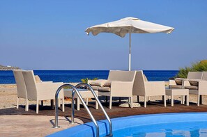 A poolside area with lounge chairs and an umbrella, overlooking the sea. - Tony's Beach (Leros)