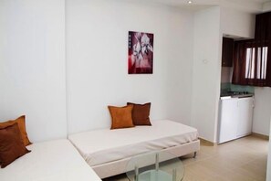 A small, modern room with a bed, a desk, and a kitchenette.