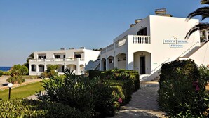 A white building with a sign reading "Tony's Beach Studios." It features multiple balconies and a pathway leading to the entrance. - Tony's Beach (Leros)
