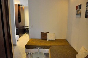 A small, modern bedroom with a single bed, a glass table, and a wardrobe.