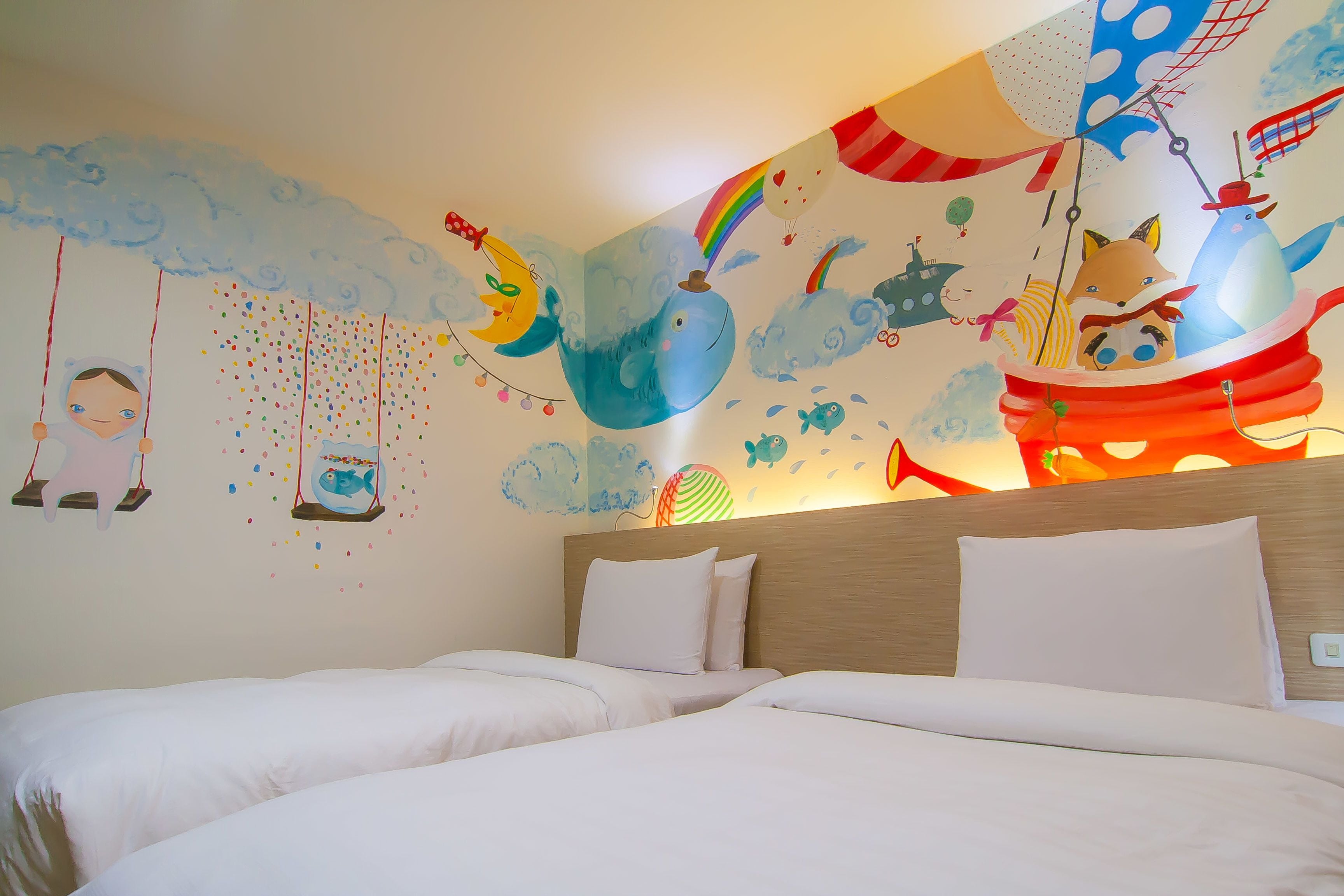 Habitación de hotel con una cama grande, cabecera de madera y un mural colorido que representa una escena fantástica con animales y un barco.