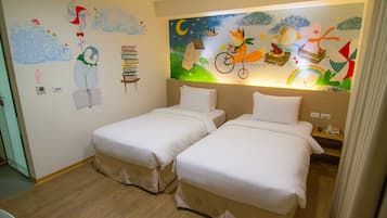 A hotel room with two beds, a mural on the wall, and a wooden floor.