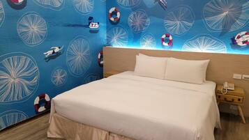 Habitación de hotel con una cama, una mesita de noche y un papel tapiz azul con motivos marinos.