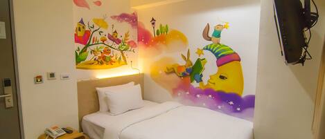 A hotel room with a bed, a bedside table with a phone, a wall-mounted TV, and a colorful mural on the wall.