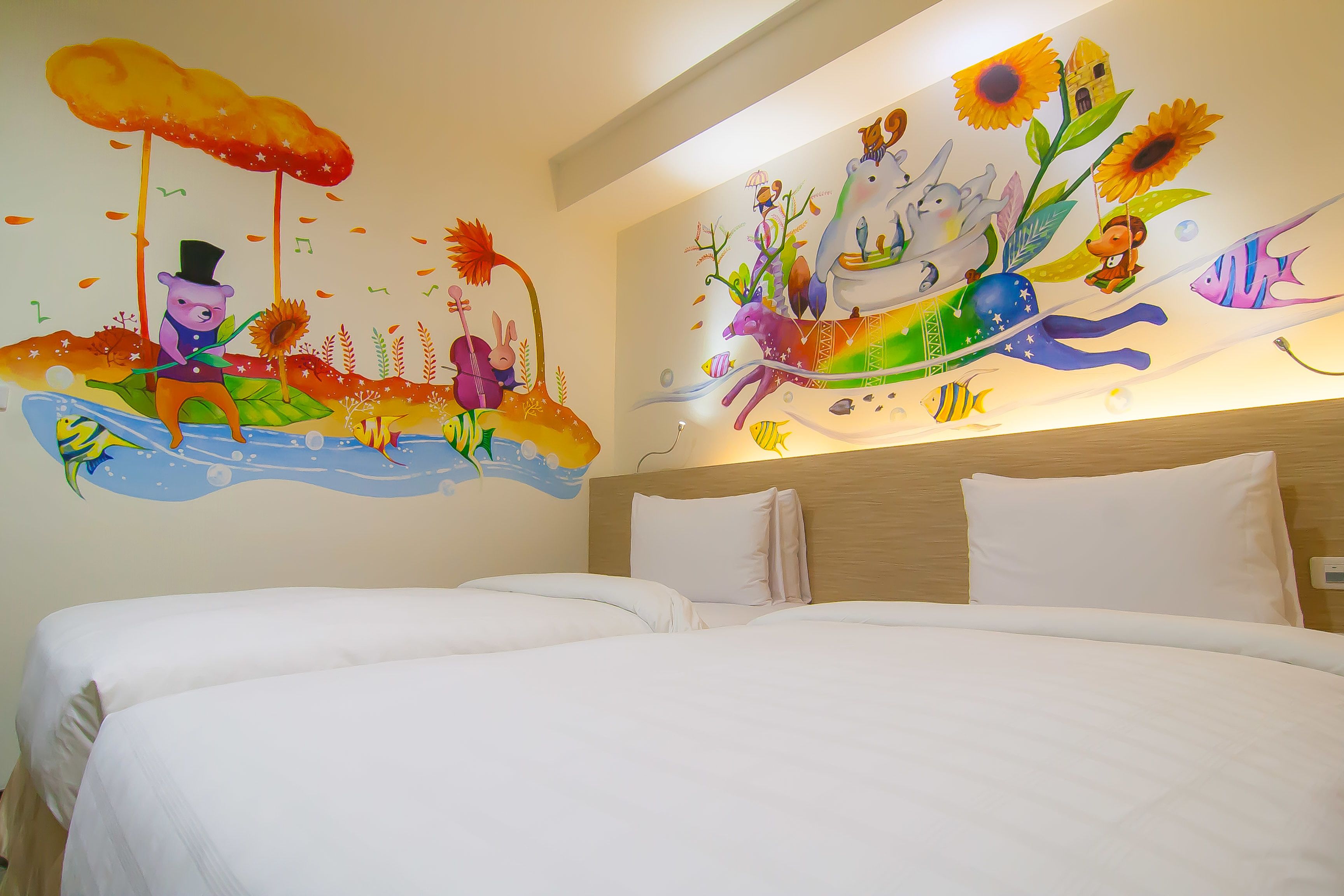 A hotel room with two beds, a mural with a whimsical design, and a wooden headboard.