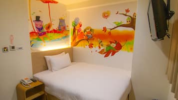 A hotel room with a bed, a nightstand with a phone, a wall mural, and a TV mounted on the wall.