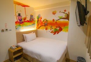 A hotel room with a bed, a nightstand with a phone, a wall mural, and a TV mounted on the wall.