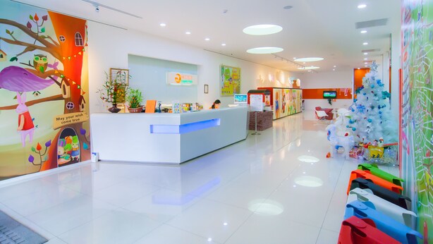 A brightly lit reception area with a white counter, a Christmas tree, and colorful wall decorations. - Legend Hotel Liuhe (Kaohsiung)