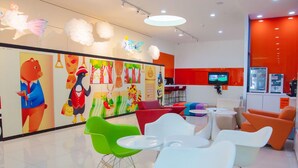 A brightly colored children's play area with colorful murals, modern seating, and a television. - Legend Hotel Liuhe (Kaohsiung)