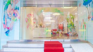 A hotel entrance with a red carpet leading to a reception desk, surrounded by colorful murals. - Legend Hotel Liuhe (Kaohsiung)