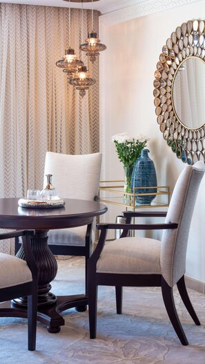 A dining area with a round table, chairs, a decorative mirror, and a vase with flowers. - One & Only Royal Mirage (Dubai)