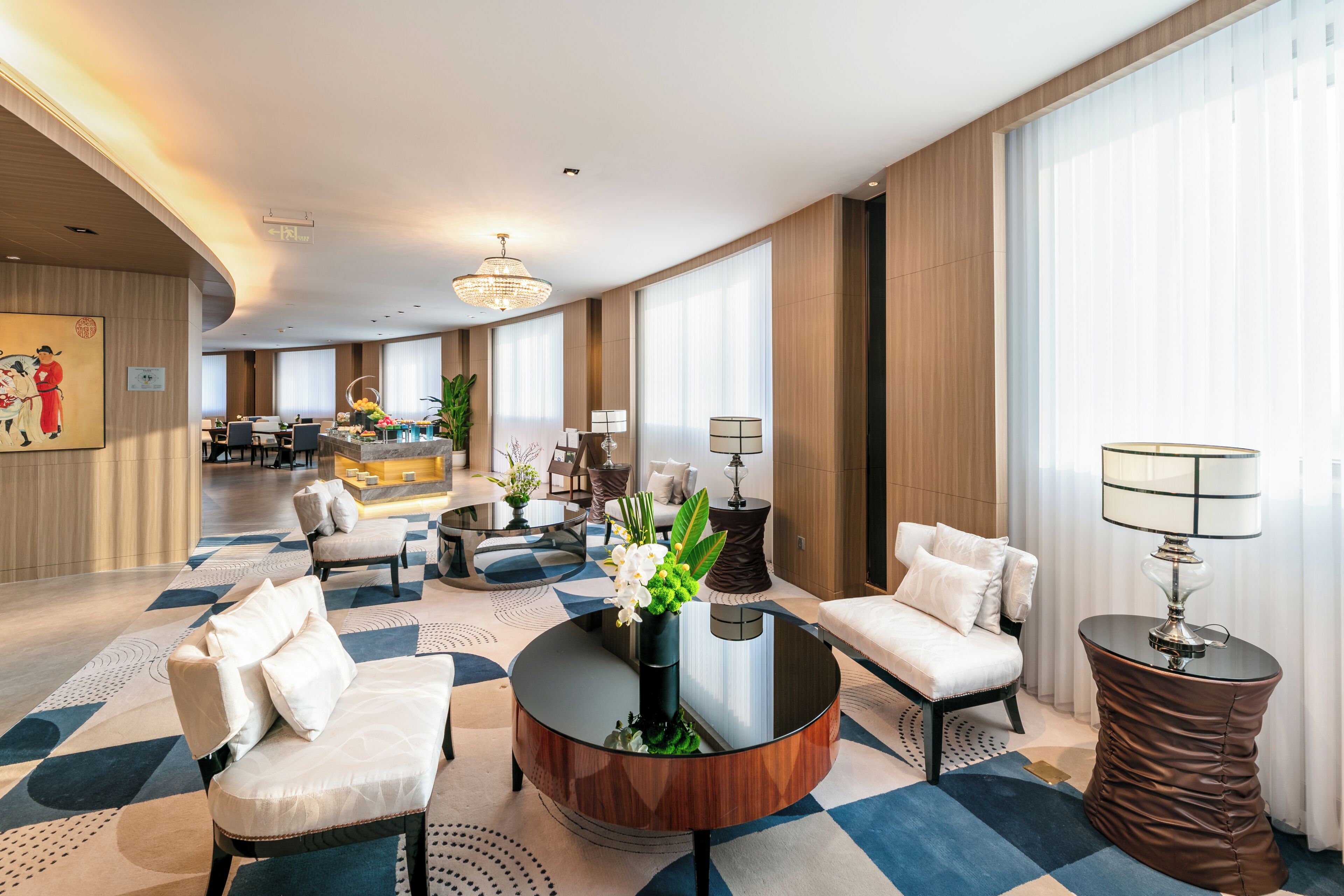 A spacious hotel lobby with a round coffee table, seating area, and a reception desk.