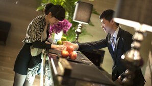 Un hombre y una mujer en la recepción, con un portátil y manzanas.