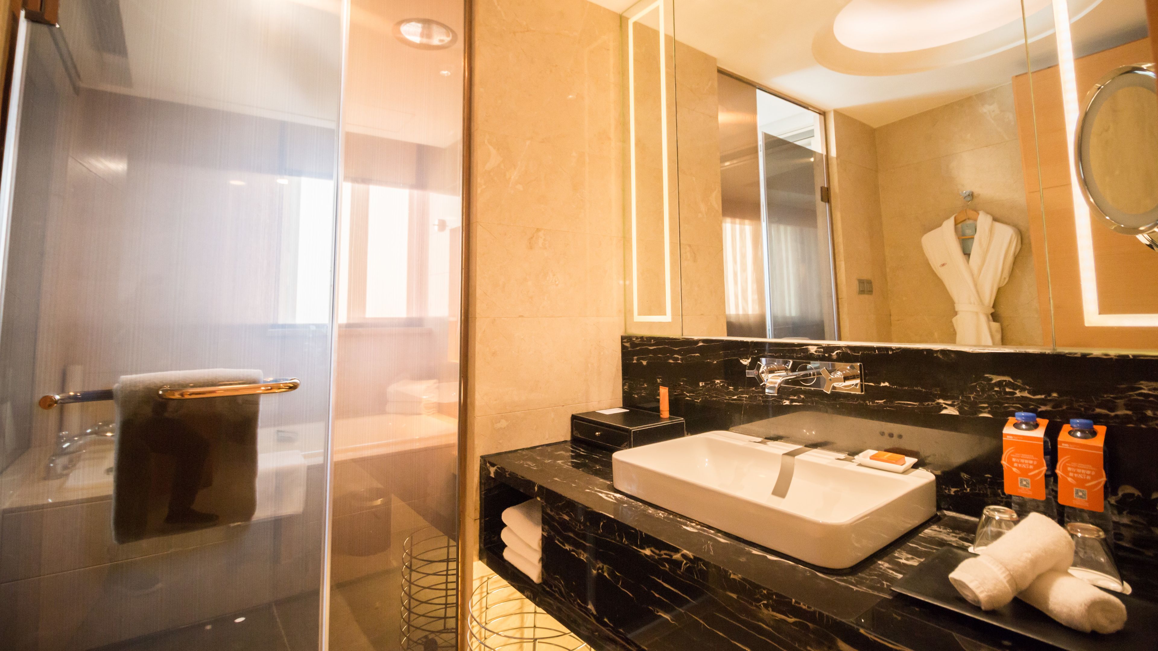 A modern bathroom with a glass shower enclosure, a large sink with a mirror above it, and a towel rack.