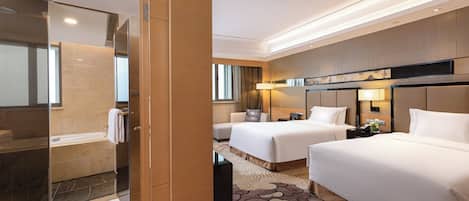 Ein Hotelzimmer mit Duschkabine aus Glas, zwei Betten, einem Nachttisch mit Lampe und einem großen Spiegel.