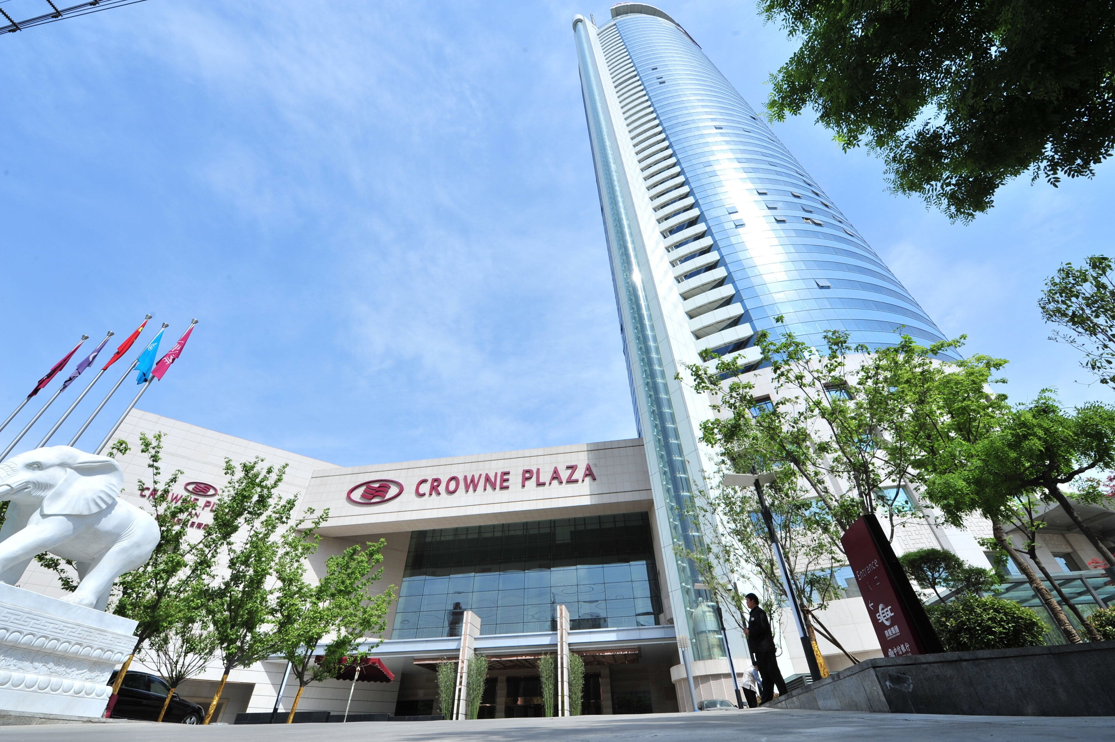 Um edifício moderno com fachada de vidro e um letreiro de 'CROWNE PLAZA' em destaque.