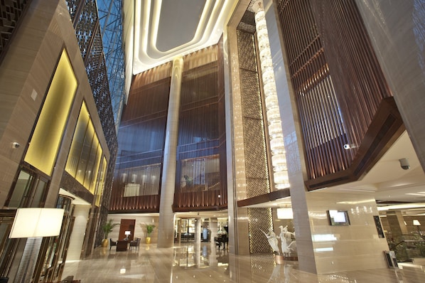 A modern hotel lobby with a high ceiling, reflective floors, and a central column. - Crowne Plaza Xian by IHG (Xi'an)